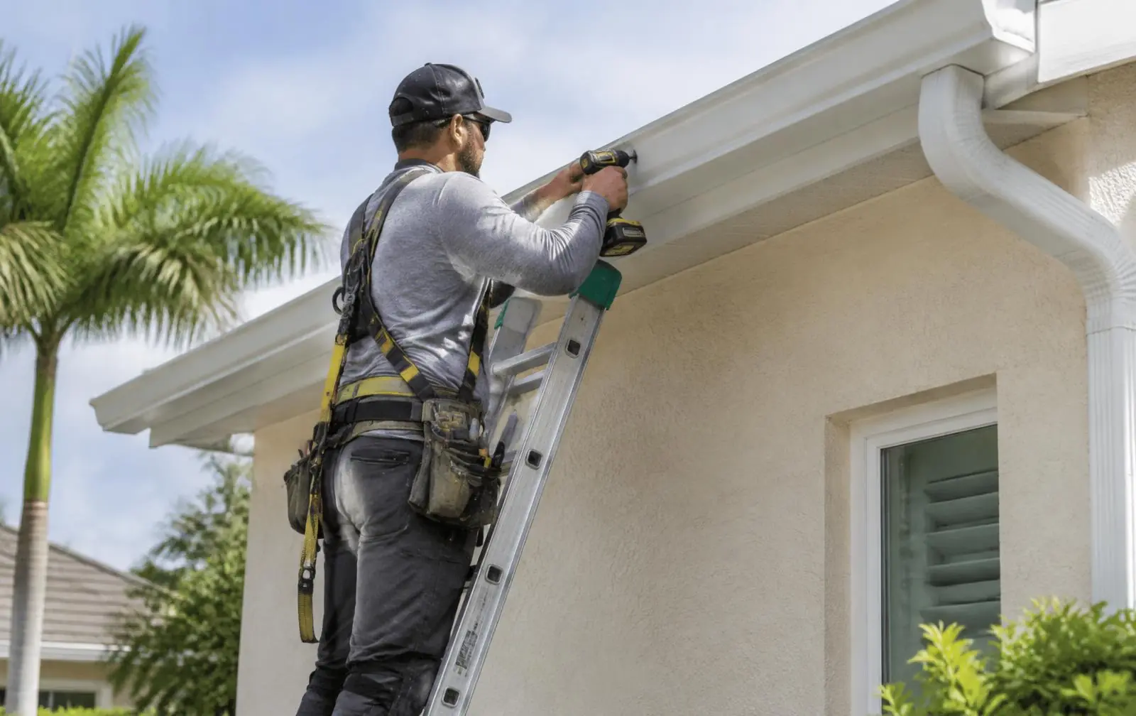 Gutter installation on a stucco home in Ocala, Florida — installer on a ladder fastening a new white gutter