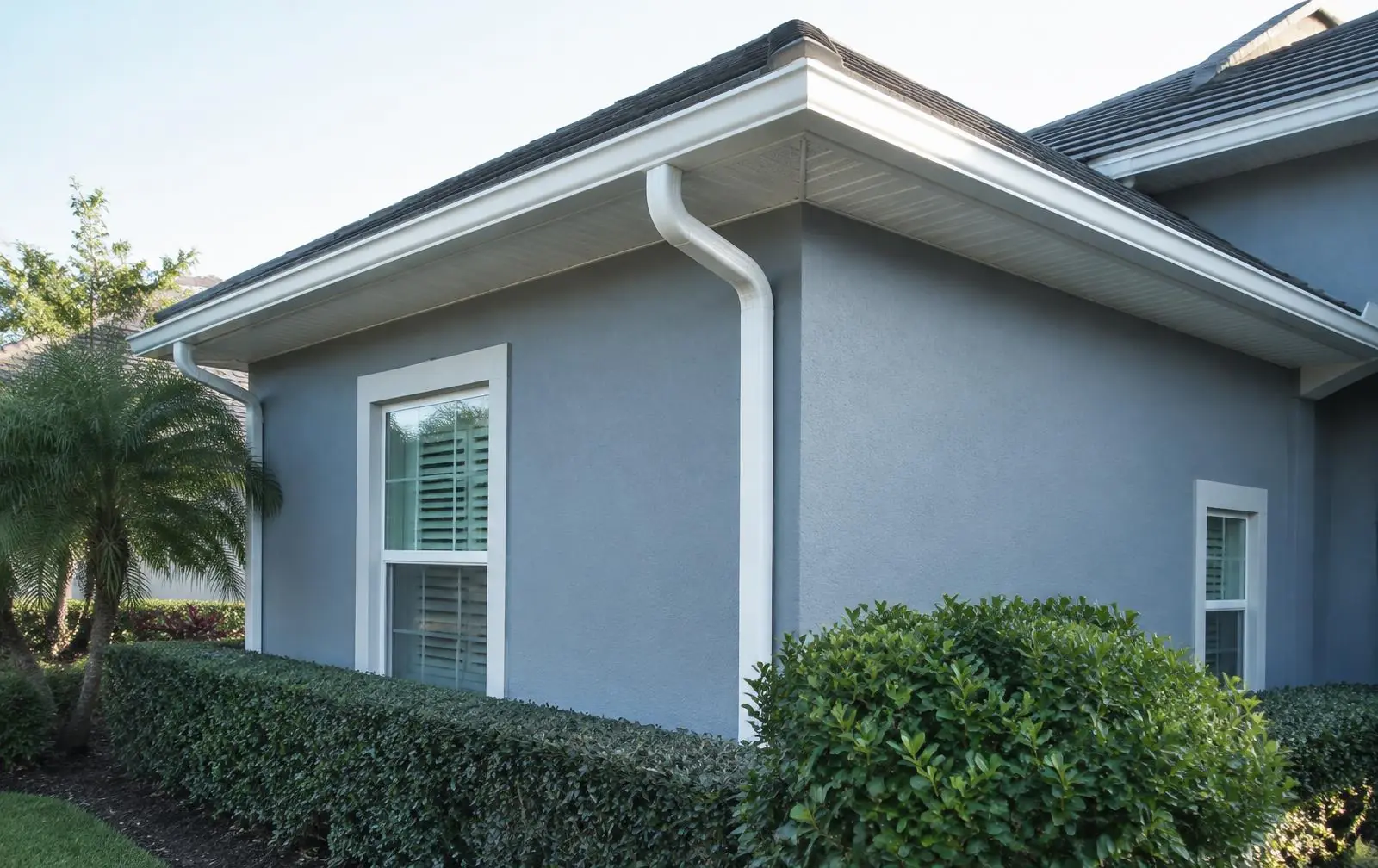 White seamless gutters and downspout wrapping the corner of a Florida stucco home